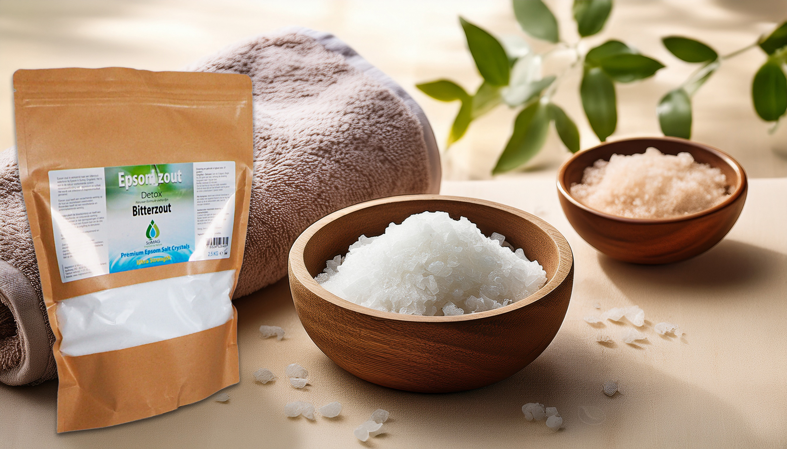 Package of Epsom salt next to wooden bowls filled with white and pink magnesium sulfate crystals, set in a wellness-themed environment with a towel and green leaves.